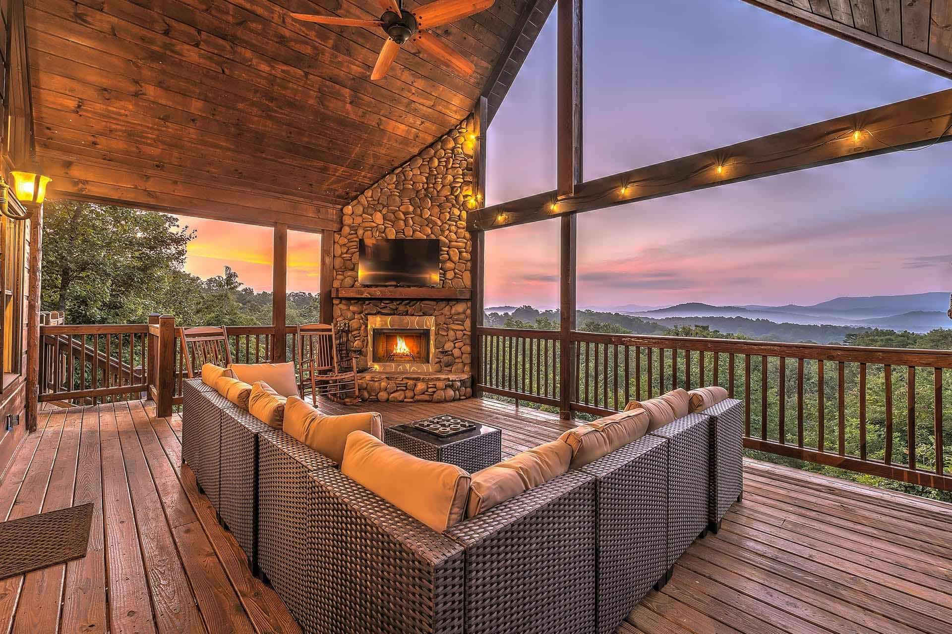 Outdoor deck with stone fireplace and mountain views at dusk
